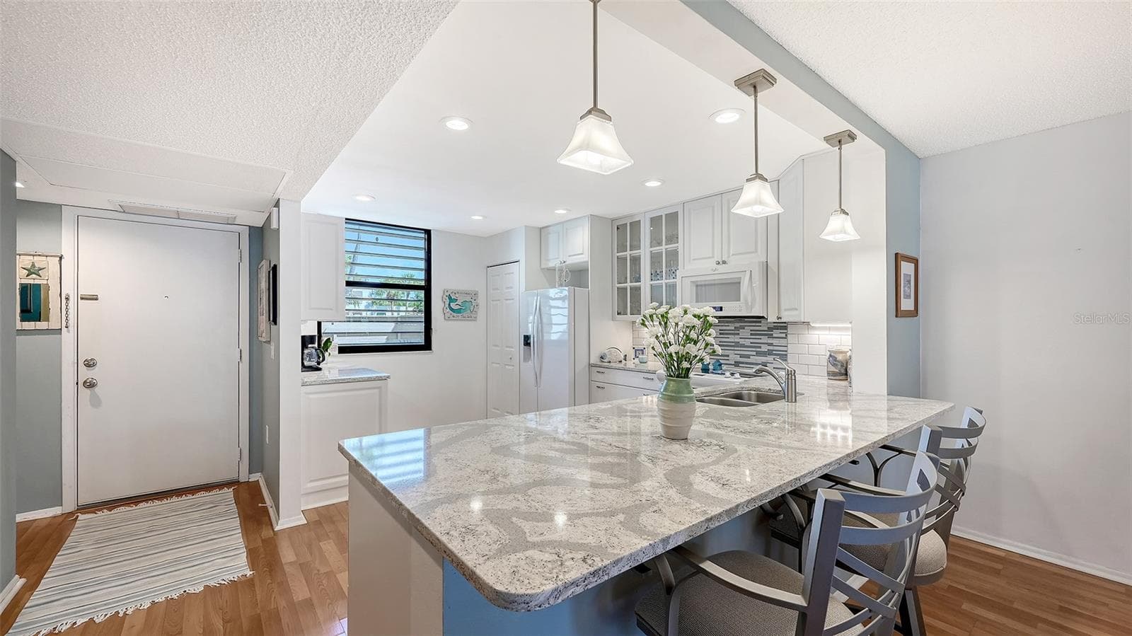 The updated open kitchen features breakfast bar, recessed lighting, and a tile backsplash. - 666 WOODLAWN DR #666, BRADENTON