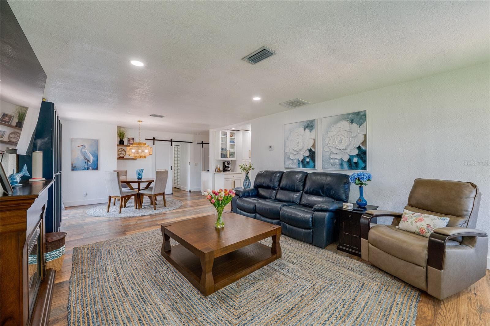 Bright and inviting interior layout featuring seamless flow between the living space and dining area, accented by a sliding barn door. - 348 WOODLAND AVE, DAYTONA BEACH