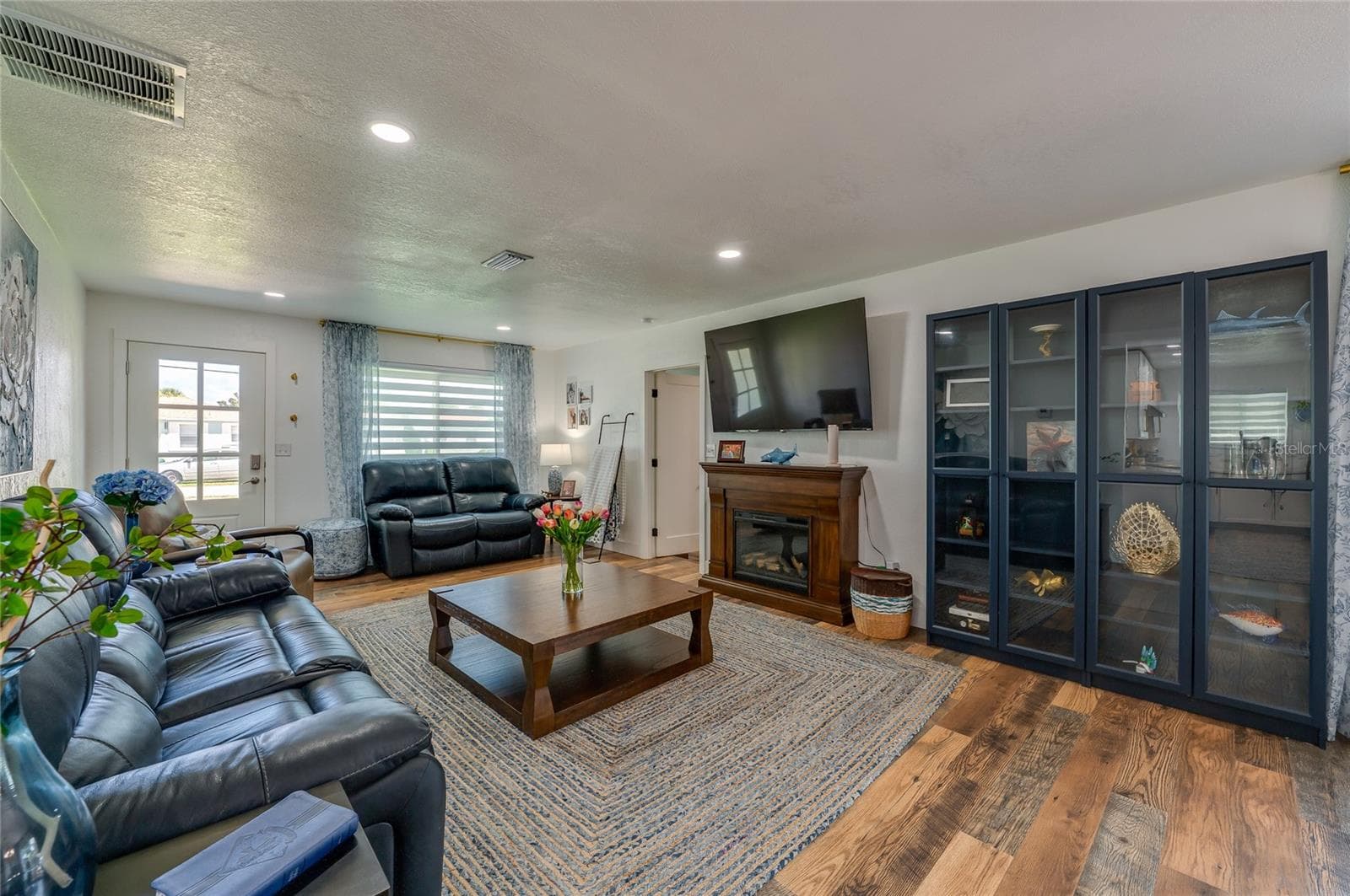 Generously sized main living space featuring rich LVP flooring under soft recessed lighting. - 348 WOODLAND AVE, DAYTONA BEACH