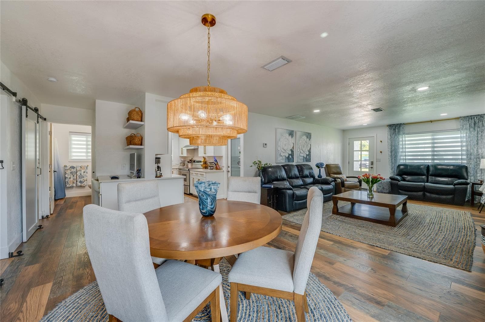 Expansive view of the open-plan main level showing the fluid transition from the dining space through to the main living area and kitchen entry. - 348 WOODLAND AVE, DAYTONA BEACH