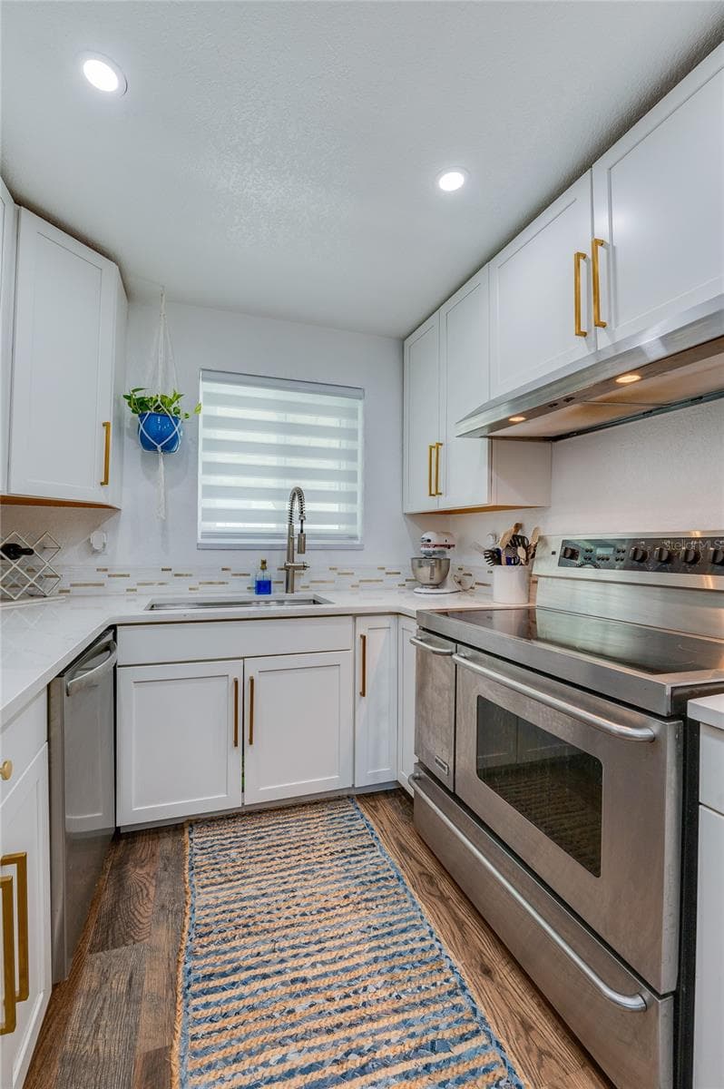 Functional kitchen workspace displaying full-size stainless steel appliances, modern quartz counters, and a window above the deep sink. - 348 WOODLAND AVE, DAYTONA BEACH