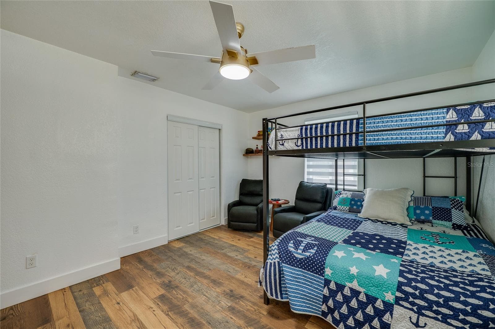 Bedroom view showcasing bright neutral walls, a ceiling fan, double sliding closet doors, and LVP flooring throughout. - 348 WOODLAND AVE, DAYTONA BEACH