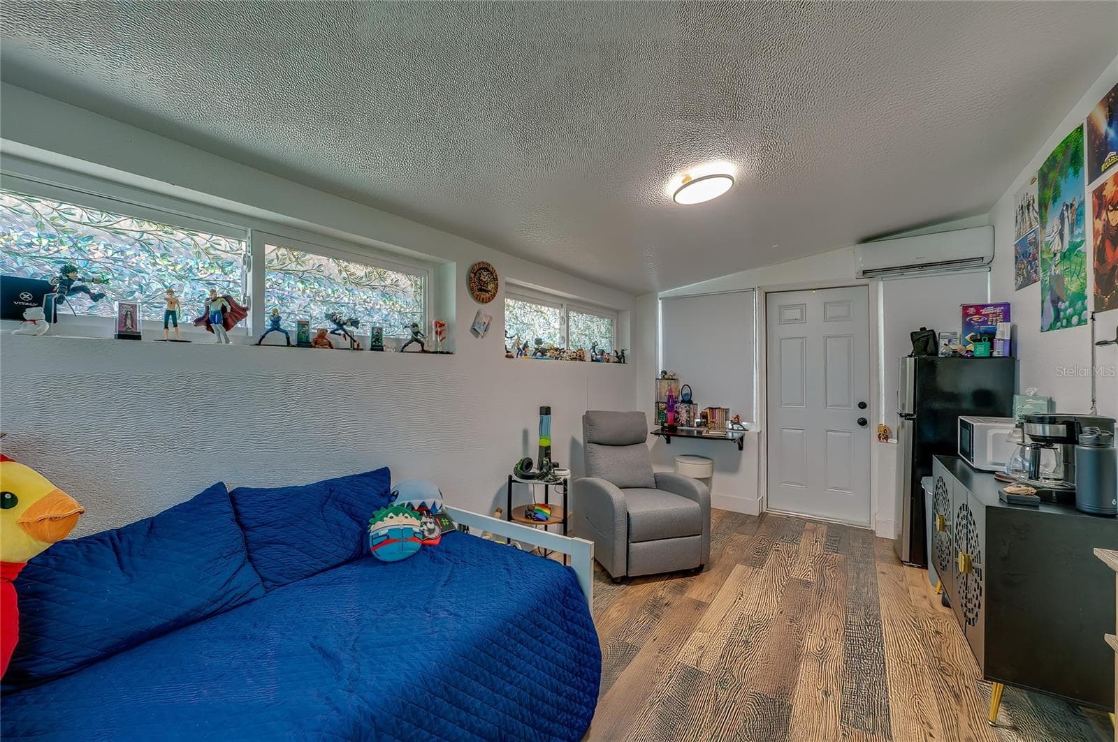 Versatile bedroom or multipurpose living space highlighting rich LVP flooring, sloped ceilings, and long horizontal windows that offer plenty of natural light. - 348 WOODLAND AVE, DAYTONA BEACH