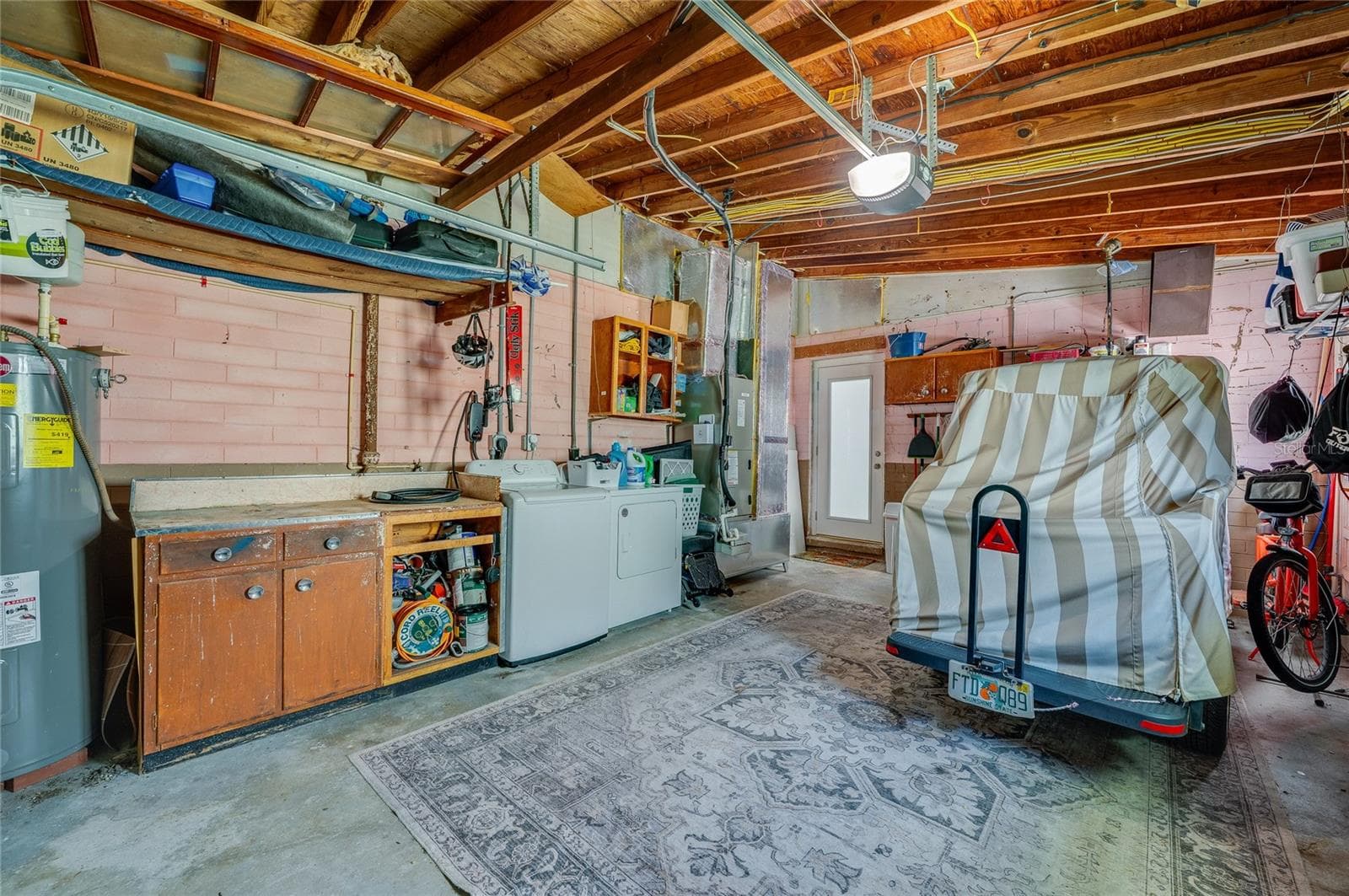 Functional garage setup complete with in-unit laundry appliances, an integrated workbench, and dedicated space for vehicle storage. - 348 WOODLAND AVE, DAYTONA BEACH