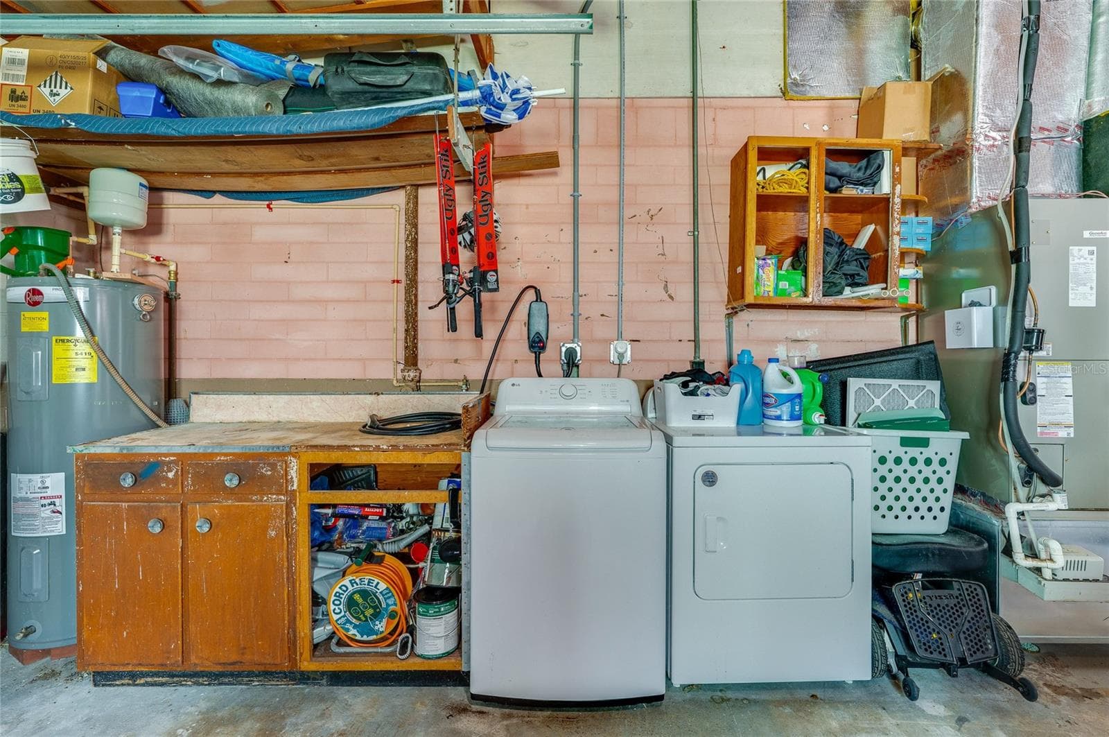 Dedicated utility station in the garage offering a washer and dryer alongside a built-in workbench and open storage shelves. - 348 WOODLAND AVE, DAYTONA BEACH