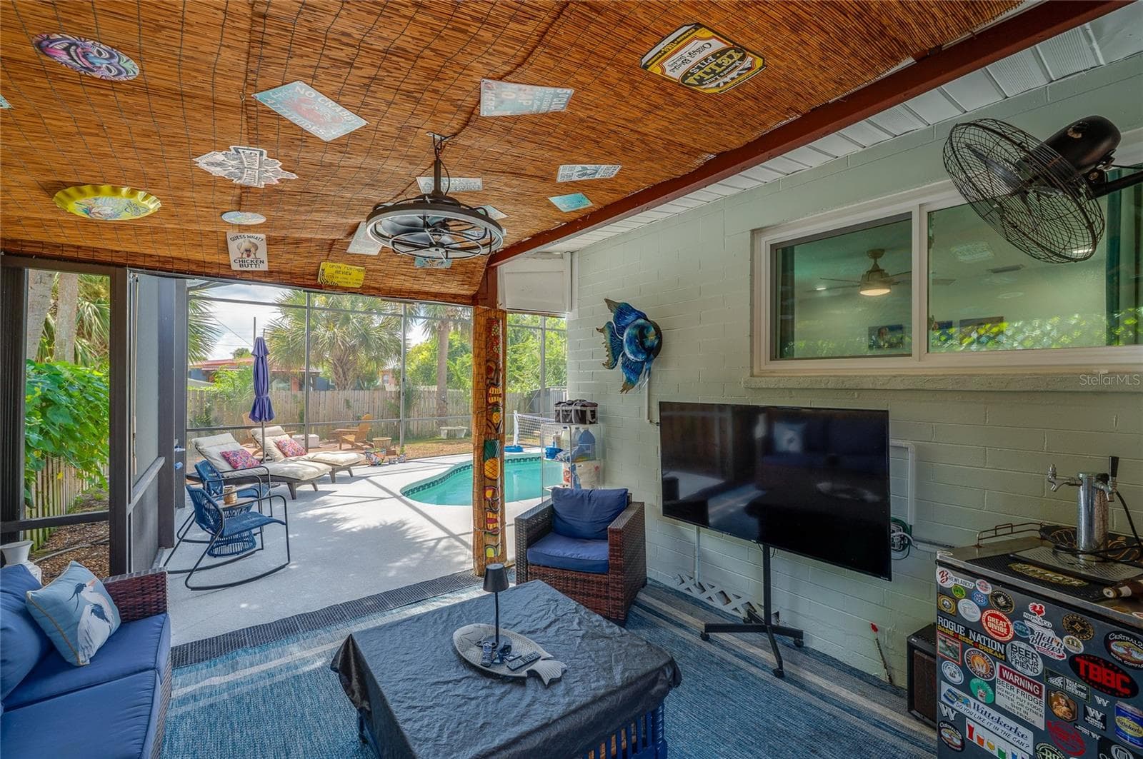 Covered screened porch featuring a woven bamboo ceiling and string lights. The space directly connects to the adjacent enclosed pool deck. - 348 WOODLAND AVE, DAYTONA BEACH