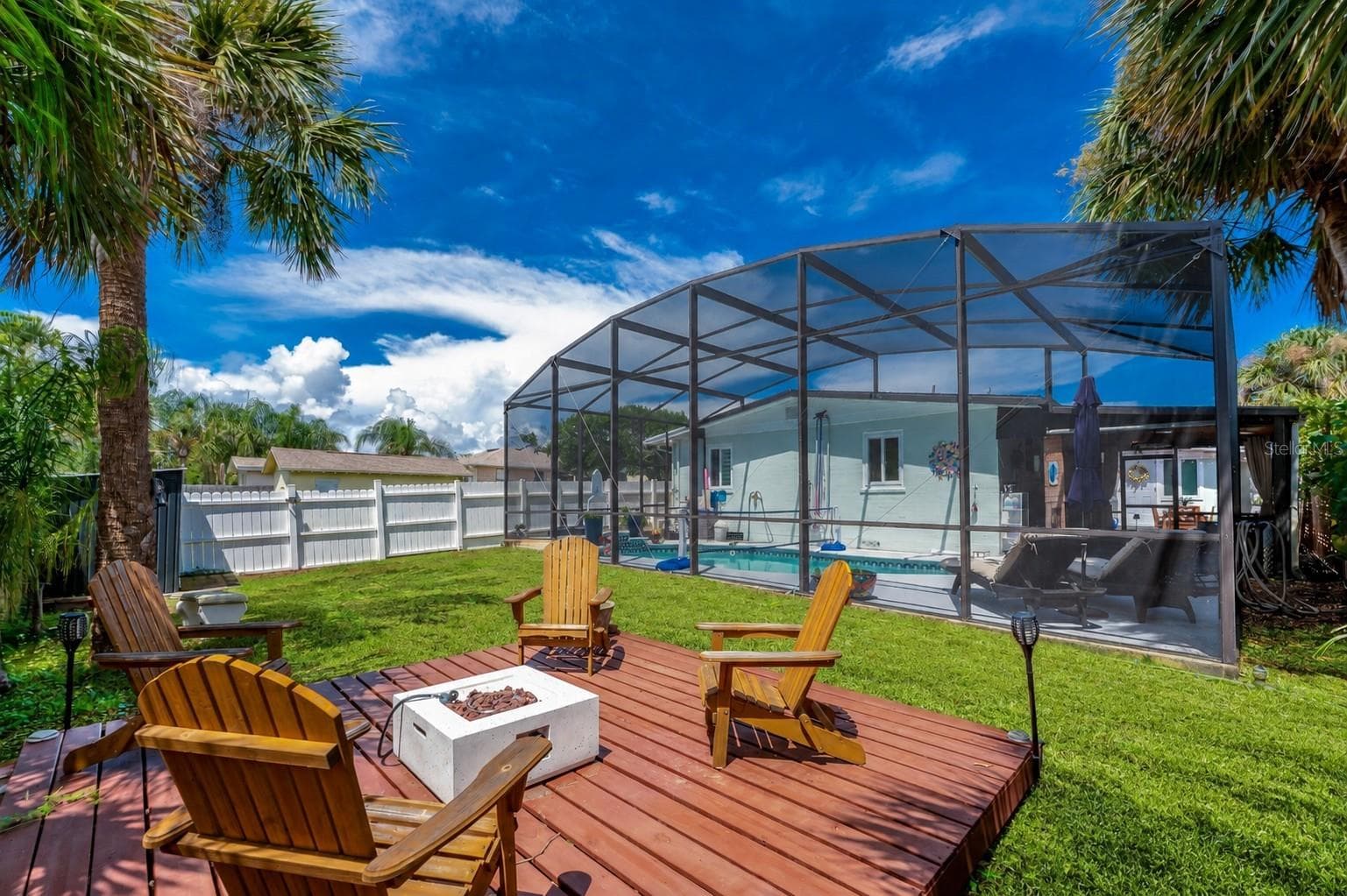 Raised wooden deck in the backyard with the screened pool enclosure and home exterior directly behind it. - 348 WOODLAND AVE, DAYTONA BEACH