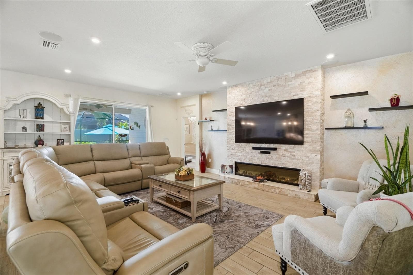 Custom stacked-stone entertainment wall with floating shelving creates a dramatic focal point in the living room. - 11750 LAKE LUCAYA DR, RIVERVIEW