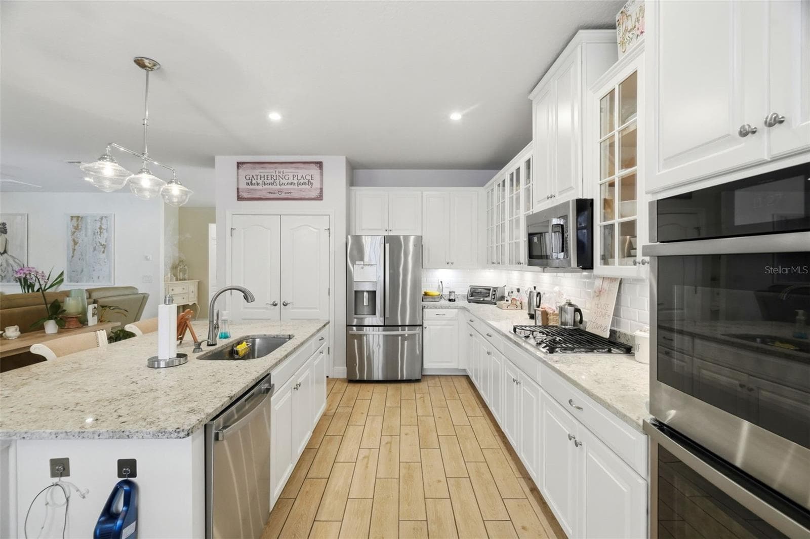 Open-concept kitchen with granite countertops, oversized island, stainless steel appliances, double wall ovens and glass-front cabinetry. - 11750 LAKE LUCAYA DR, RIVERVIEW