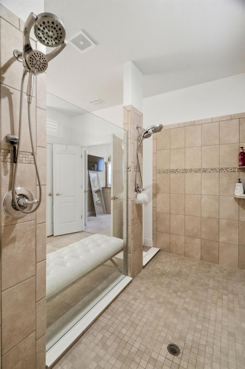 Oversized tiled walk-in shower with built-in bench and multiple shower niches. - 11750 LAKE LUCAYA DR, RIVERVIEW