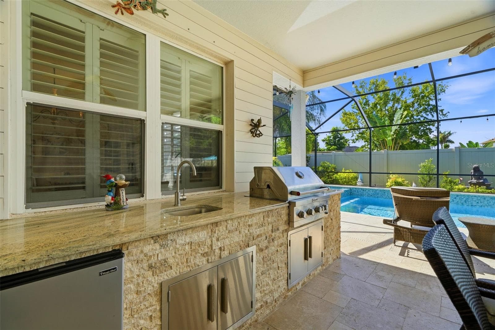 Custom outdoor kitchen with granite countertop, built-in grill, refrigerator and sink. - 11750 LAKE LUCAYA DR, RIVERVIEW