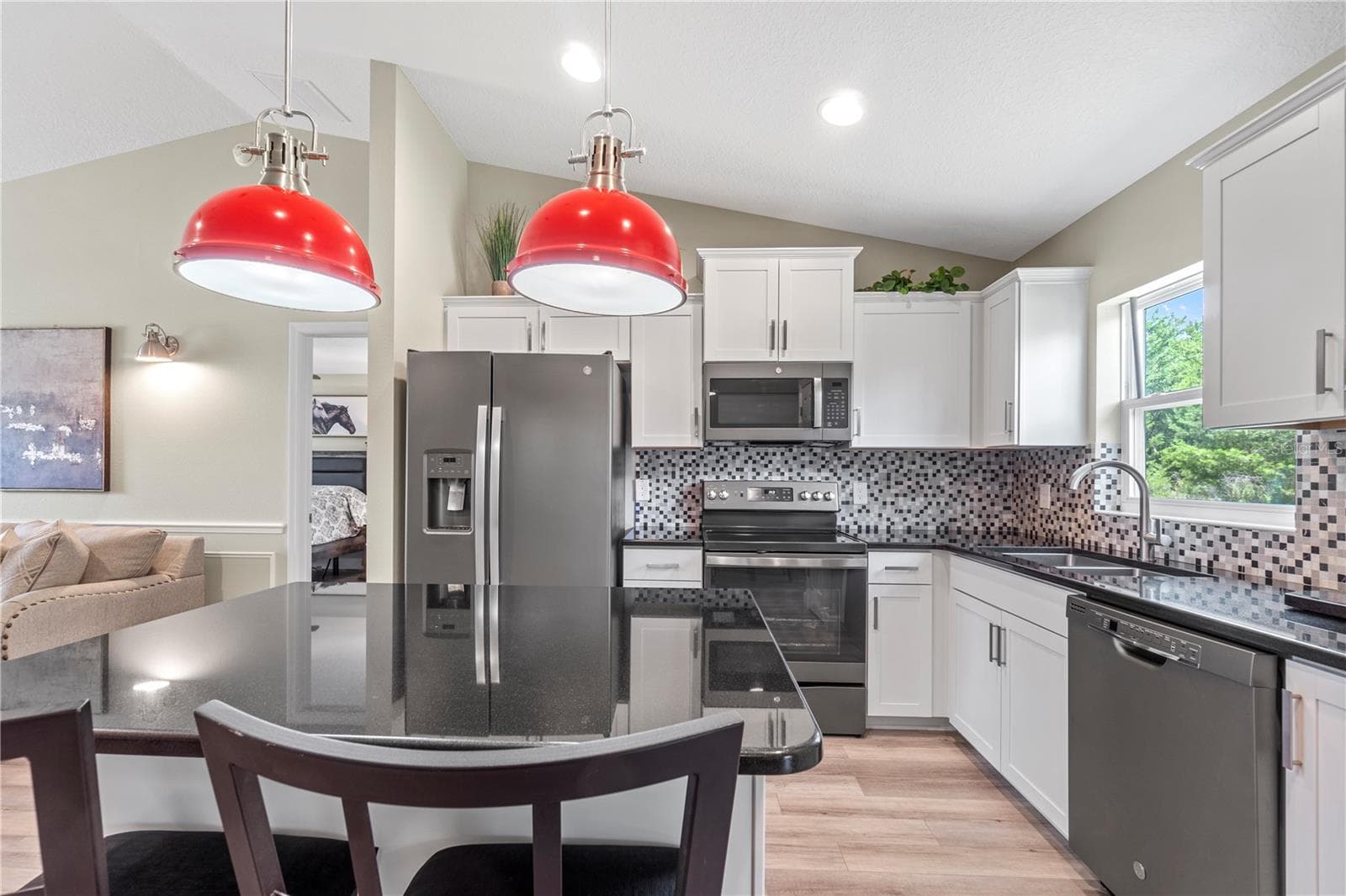 Open-concept kitchen with custom granite counters and hardwood soft-close cabinetry. - 15994 SW 55TH AVENUE RD, OCALA