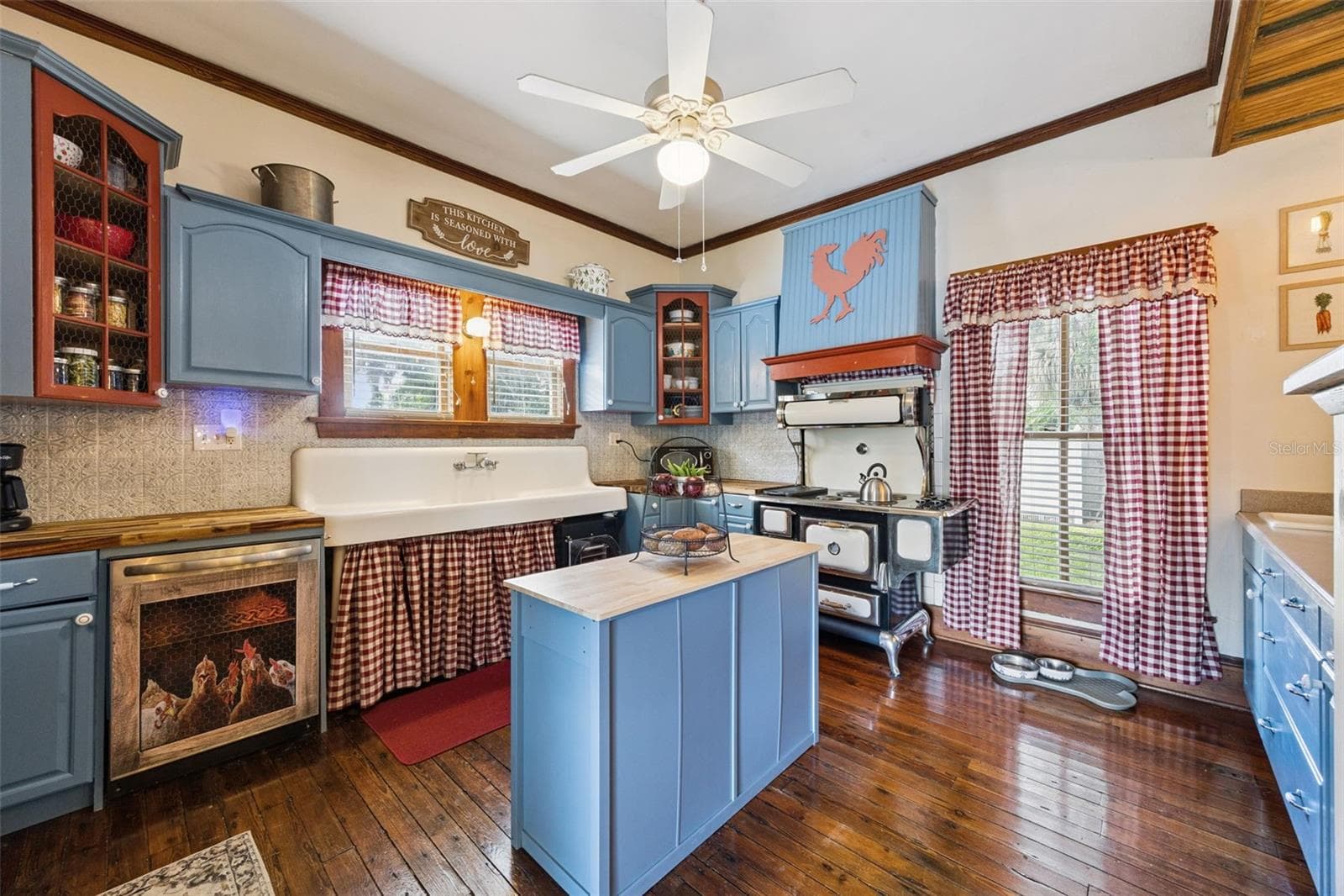 Full of personality, the kitchen pairs blue cabinetry and warm wood floors with a farmhouse sink and striking vintage-style range. - 2201 CELERY AVE, SANFORD