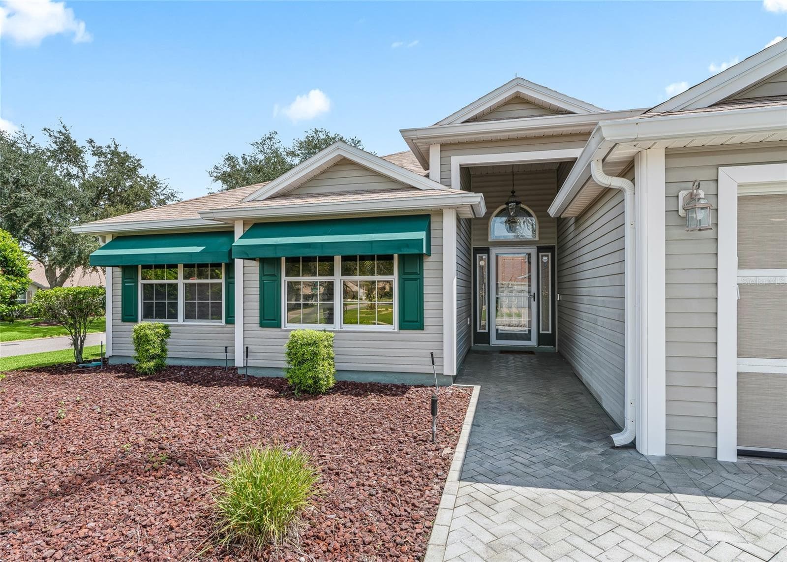 Welcoming covered front entry with paver walkway, decorative glass front door, sidelights and transom window bringing natural light into the foyer. - 17601 SE 81ST TIMBERWOOD TER, THE VILLAGES