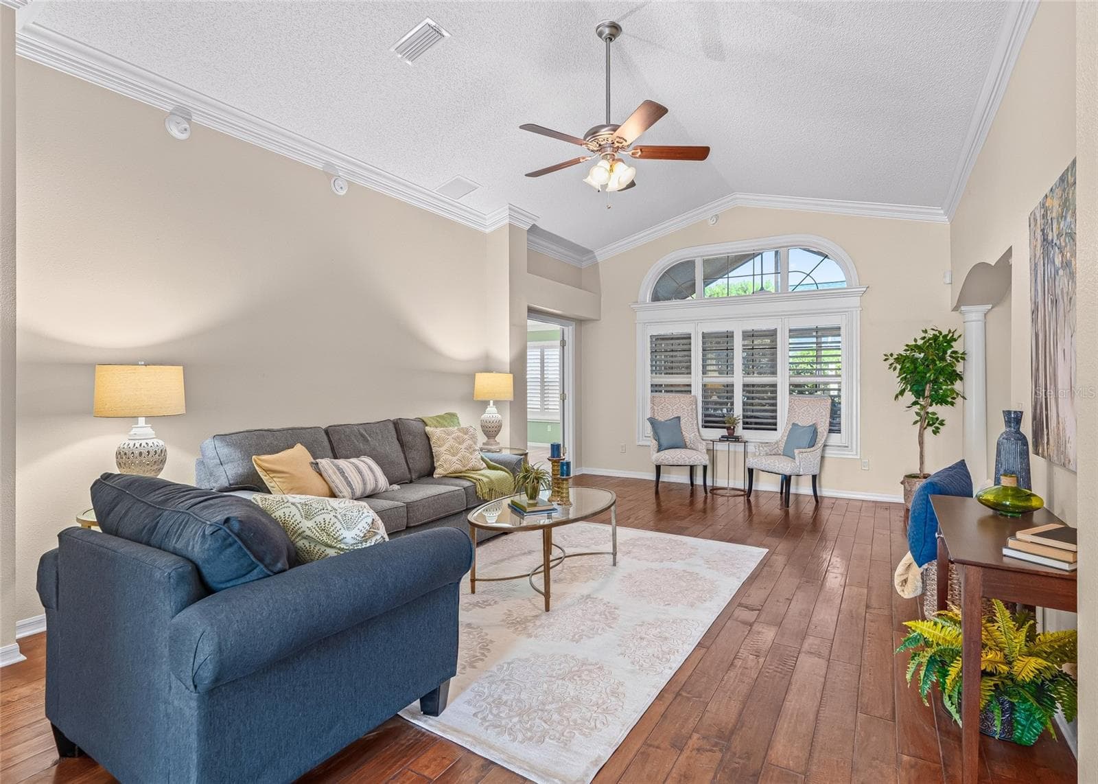 Spacious Living Room features vaulted ceilings, beautiful crown molding, warm wood flooring and PLANTATION SHUTTERS surrounding the large front windows. - 17601 SE 81ST TIMBERWOOD TER, THE VILLAGES
