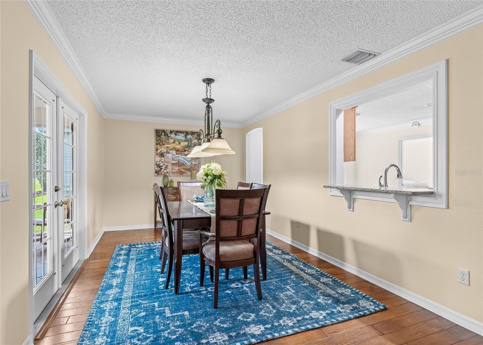 Spacious Formal Dining Room with crown molding, French doors to the Florida Room, and a convenient pass-through to the kitchen—great for entertaining. - 17601 SE 81ST TIMBERWOOD TER, THE VILLAGES