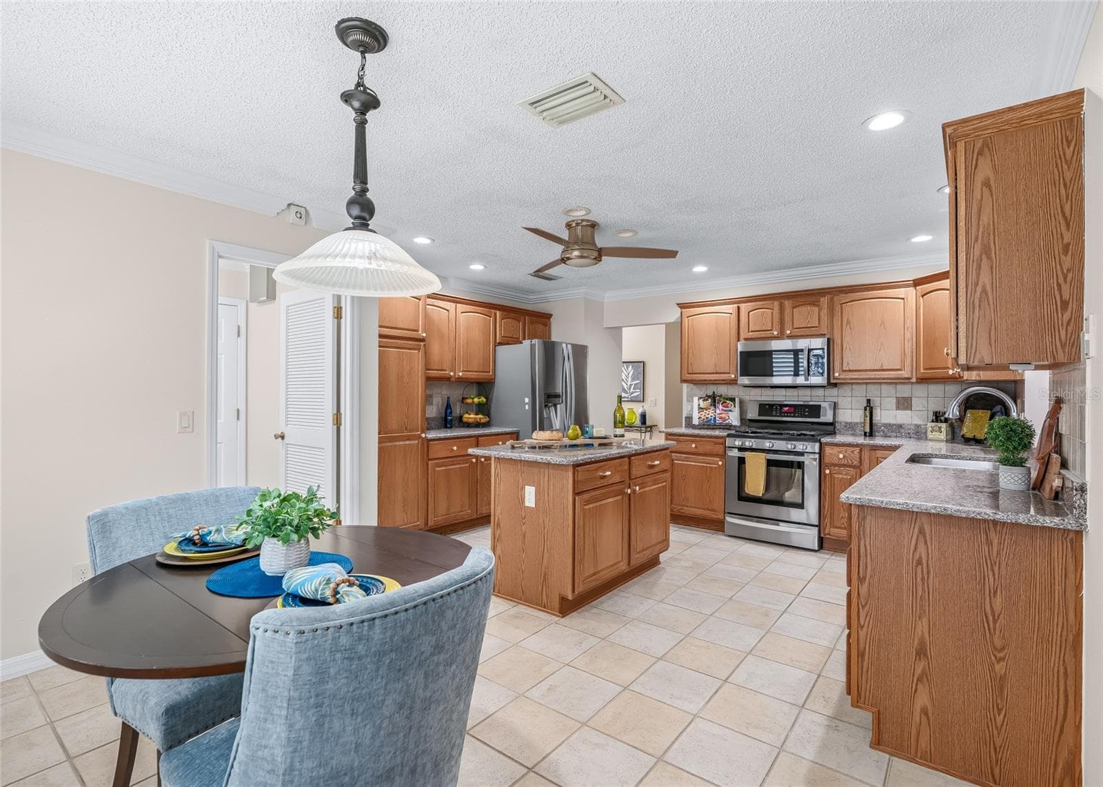 Spacious eat-in kitchen offers a center island, plentiful cabinetry and counter space, stainless appliances, recessed lighting and room for a casual dining table. - 17601 SE 81ST TIMBERWOOD TER, THE VILLAGES