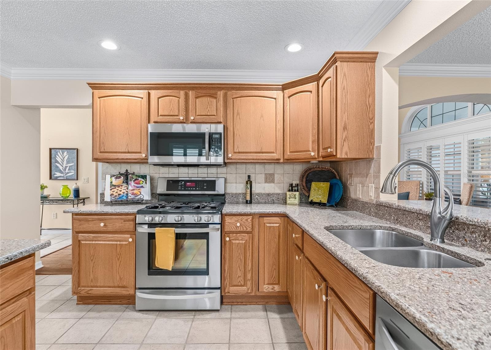 Functional kitchen layout includes a gas range, stainless microwave and dishwasher, double-basin sink, abundant cabinetry and a convenient pass-through overlooking the living area. - 17601 SE 81ST TIMBERWOOD TER, THE VILLAGES