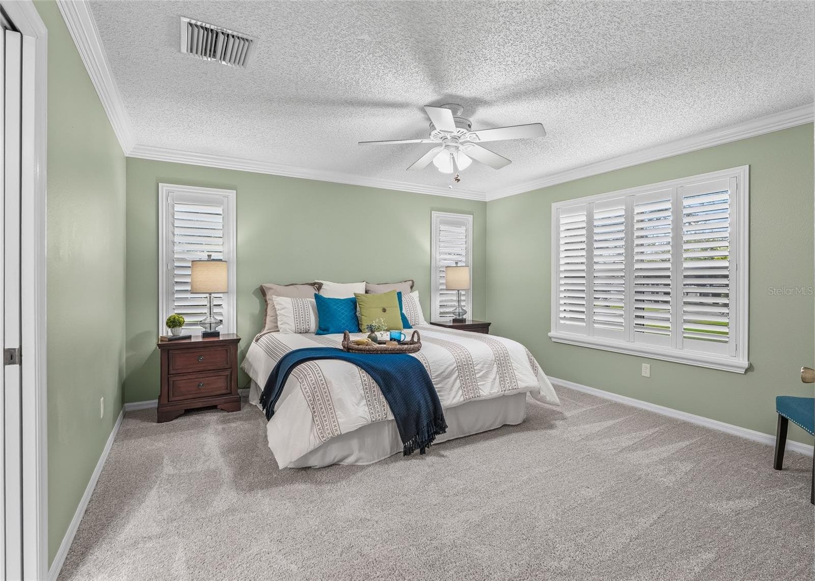 Spacious PRIMARY BEDROOM with crown molding, plantation shutters, ceiling fan and BRAND-NEW, never-lived-on plush carpeting. - 17601 SE 81ST TIMBERWOOD TER, THE VILLAGES