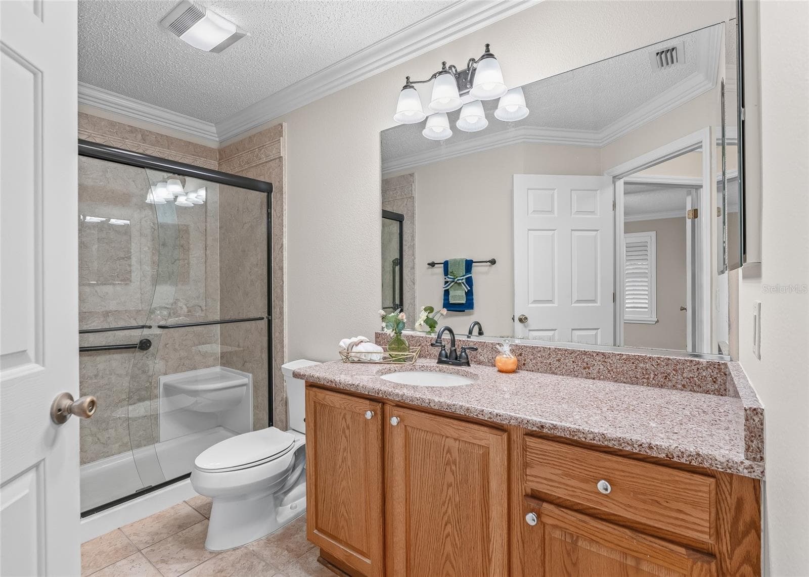 Beautiful Guest Bath features a large vanity with abundant counter space, crown molding and an upgraded walk-in shower with glass enclosure. - 17601 SE 81ST TIMBERWOOD TER, THE VILLAGES