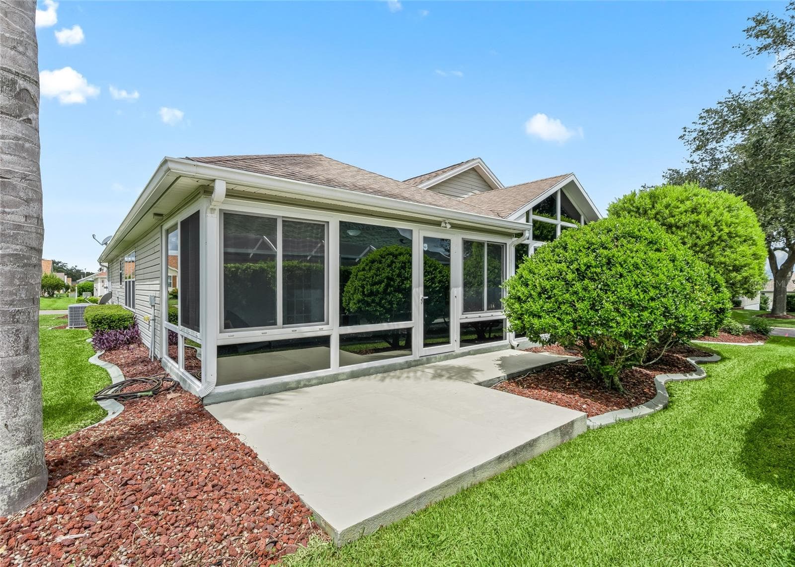 Exterior view of the enclosed Florida Room shows the substantial addition, large windows and easy access to the surrounding yard and patio area. - 17601 SE 81ST TIMBERWOOD TER, THE VILLAGES