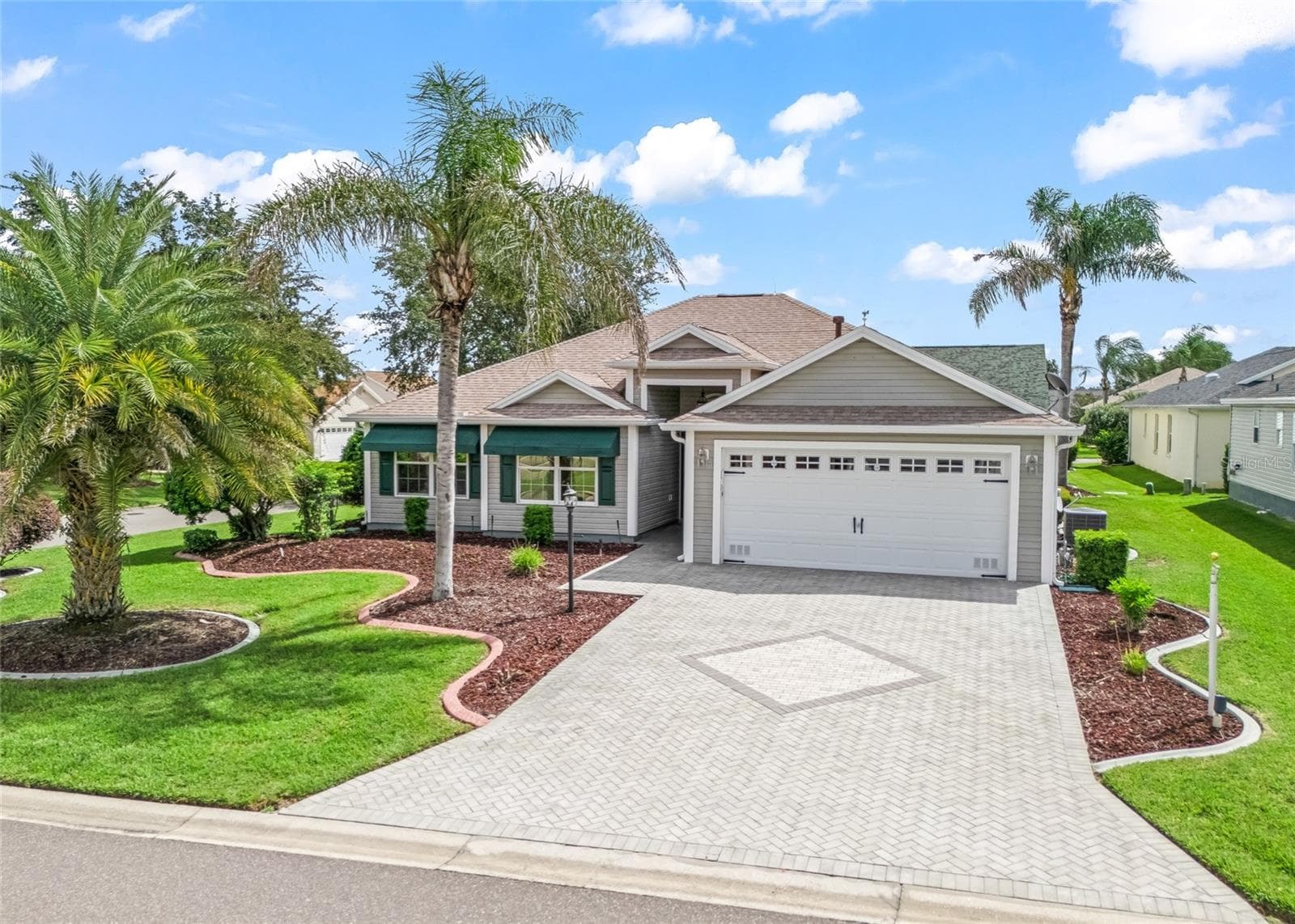 This front view showcases the home’s attractive curb appeal, mature landscaping, wide paver driveway and desirable CORNER LOT setting. - 17601 SE 81ST TIMBERWOOD TER, THE VILLAGES