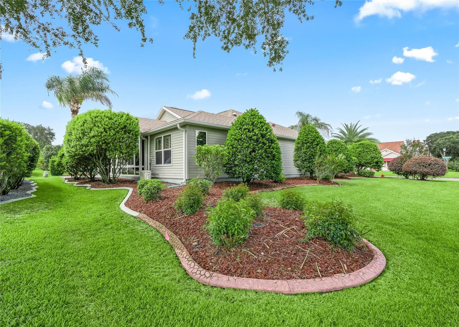 The oversized corner setting provides a wonderful sense of openness, with beautifully maintained lawn, mature shrubs and landscaped beds wrapping around the home. - 17601 SE 81ST TIMBERWOOD TER, THE VILLAGES