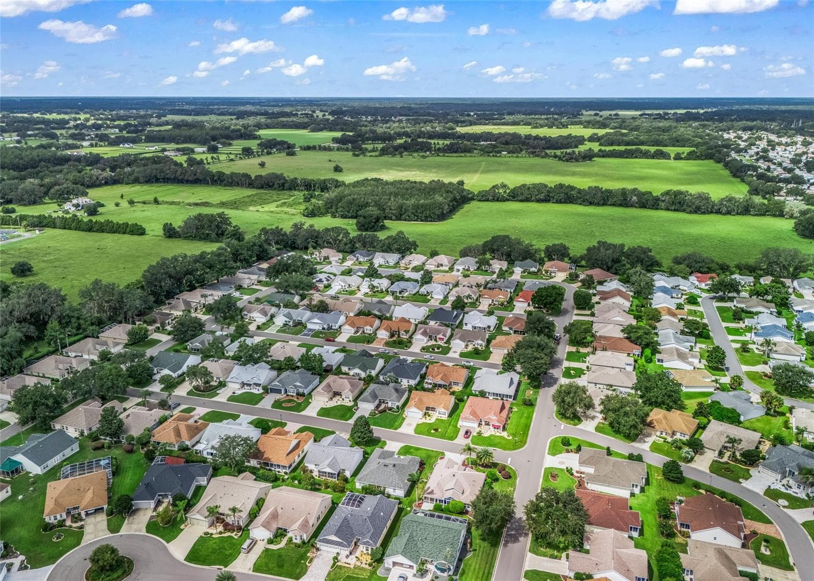 Wide aerial view showcases the peaceful residential setting of the Village of Piedmont, surrounded by mature landscaping and the open green spaces that help give this area such an established feel. - 17601 SE 81ST TIMBERWOOD TER, THE VILLAGES