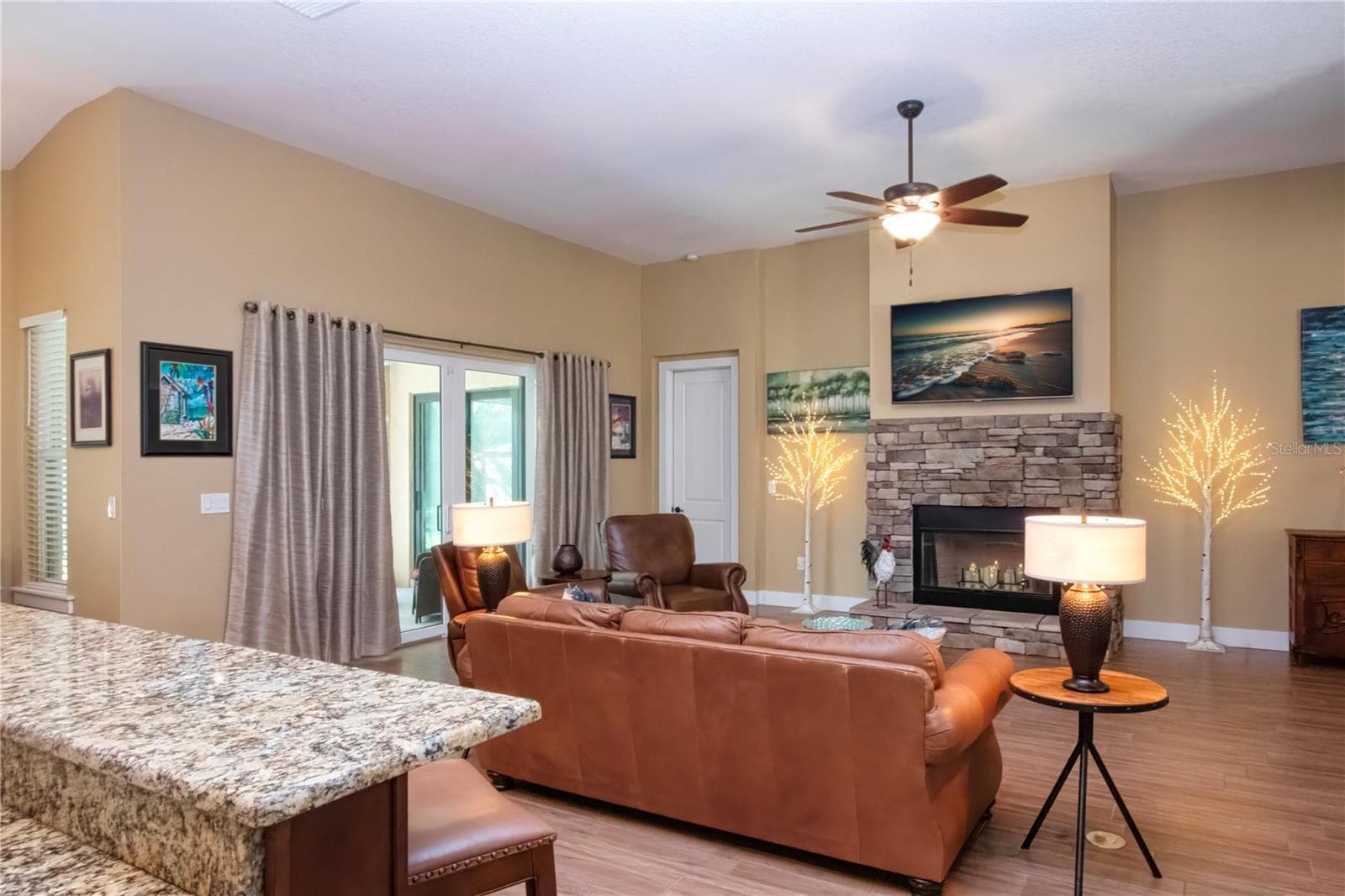 Open floor plan with view of the livingroom and fireplace that overlooks triple sliding impact doors to the screened in lanai and fenced in area - 1605 BUTCH CASSIDY TRL, WIMAUMA