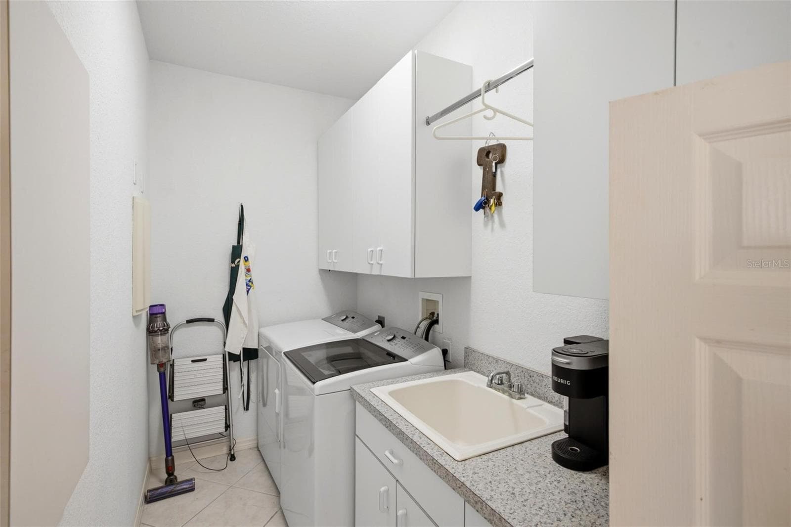 Laundry room has saloon style doors, a sink, cabinet and counter space for extra storage options. - 209 DIVINCI DR, PUNTA GORDA