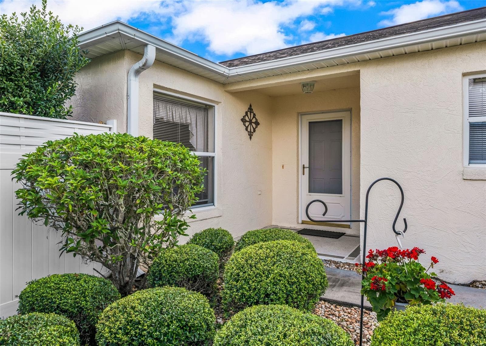 Inviting front entrance featuring a charming covered porch overhang, attractive front door, and a welcoming sidewalk leading to the entry. The thoughtfully designed entrance adds to the home’s warm curb appeal and creates a lovely first impression - 17535 SE 84TH FOXGROVE AVE, THE VILLAGES