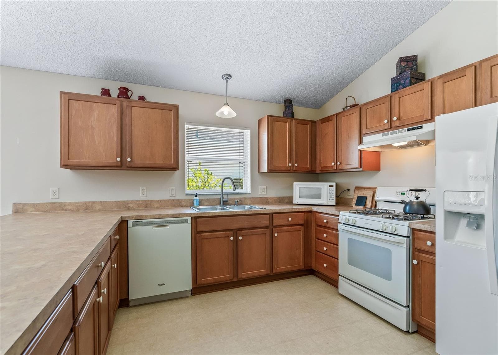 Bright and inviting kitchen featuring beautiful solid maple cabinetry, providing abundant storage and a warm, natural feel. The well-appointed kitchen offers plenty of counter space and a spacious layout that flows seamlessly into the living area, making it ideal for both everyday living and entertaining. - 17535 SE 84TH FOXGROVE AVE, THE VILLAGES