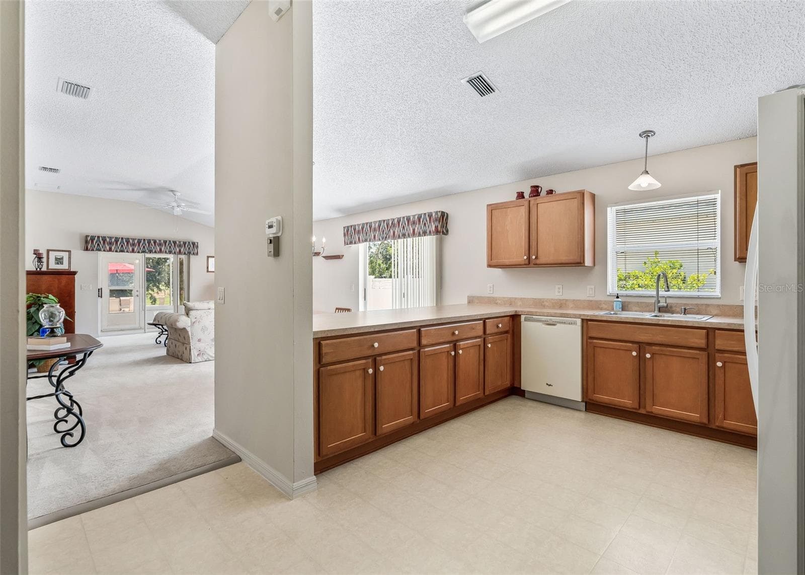 Bright and inviting open-concept living and kitchen space featuring vaulted ceilings that create an airy, spacious feel. The seamless flow between the kitchen and living area makes this home perfect for comfortable everyday living and entertaining. - 17535 SE 84TH FOXGROVE AVE, THE VILLAGES