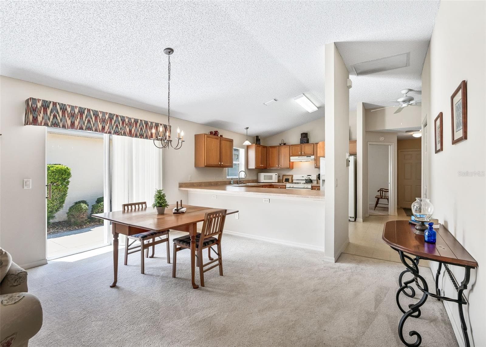 Bright and inviting dining area featuring a large breakfast bar and sliding glass doors that provide easy access to the patio. The open layout creates a wonderful space for casual dining, entertaining, and enjoying the Florida lifestyle. - 17535 SE 84TH FOXGROVE AVE, THE VILLAGES