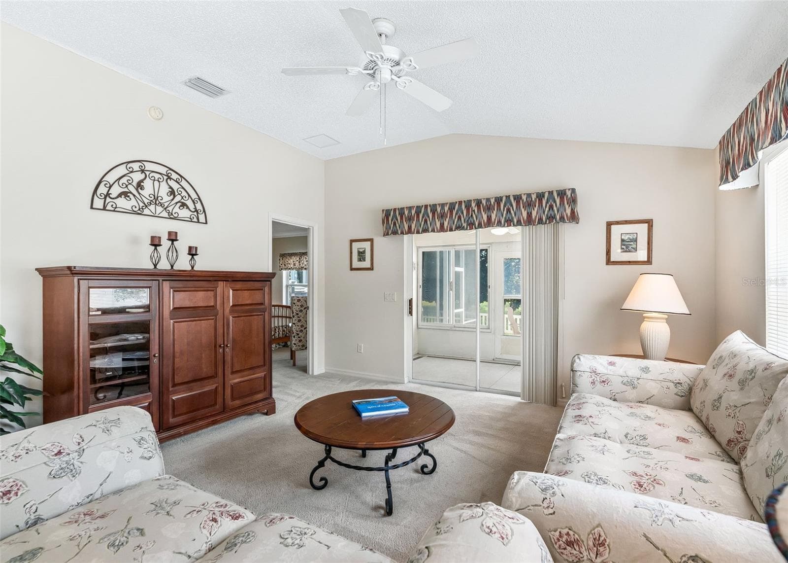 Bright and inviting living space featuring sliding door access to the enclosed lanai, where you can relax and enjoy beautiful views overlooking the golf course. The open layout creates a comfortable connection between the indoor and outdoor living areas, making this a wonderful space for relaxing or entertaining. - 17535 SE 84TH FOXGROVE AVE, THE VILLAGES
