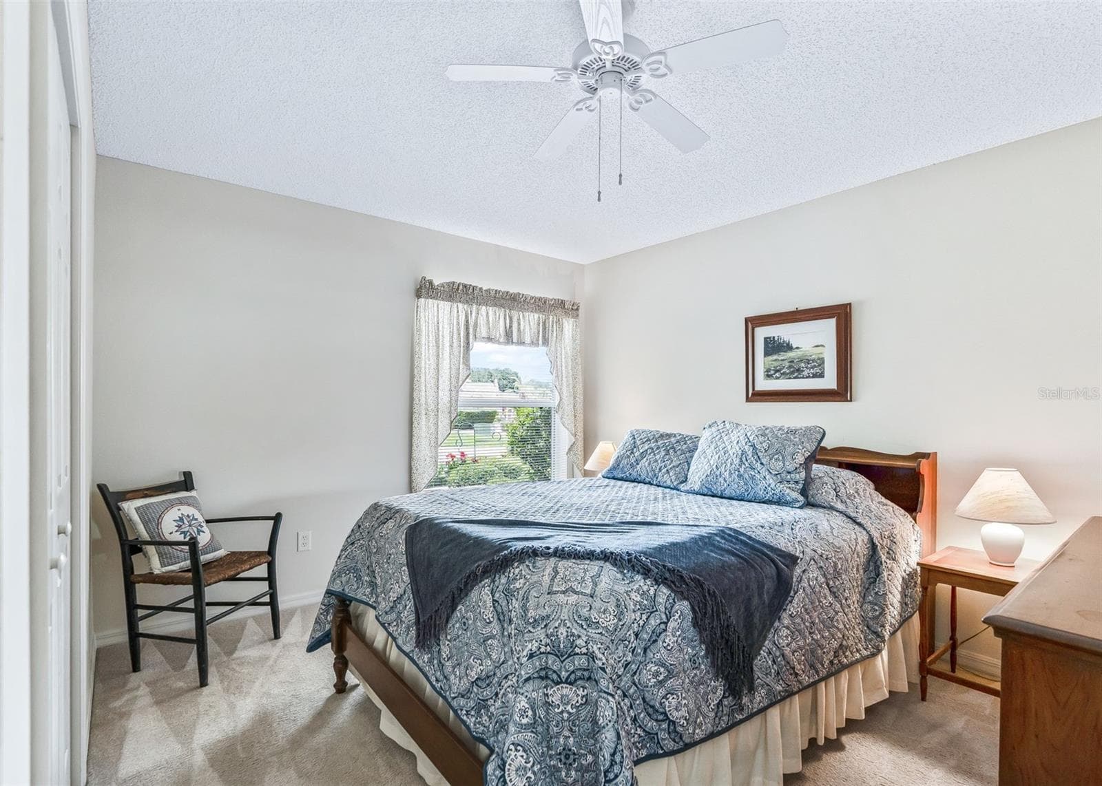 Bright and inviting guest bedroom featuring a ceiling fan and a comfortable layout, creating a welcoming retreat that is perfect for family and overnight guests. - 17535 SE 84TH FOXGROVE AVE, THE VILLAGES