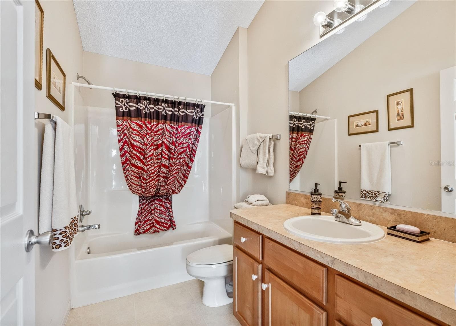 Guest bathroom featuring a convenient tub and shower combination with coordinating Autumn Maple cabinetry that continues the warm, inviting style of the home. The functional layout provides comfort and convenience for family and guests. - 17535 SE 84TH FOXGROVE AVE, THE VILLAGES