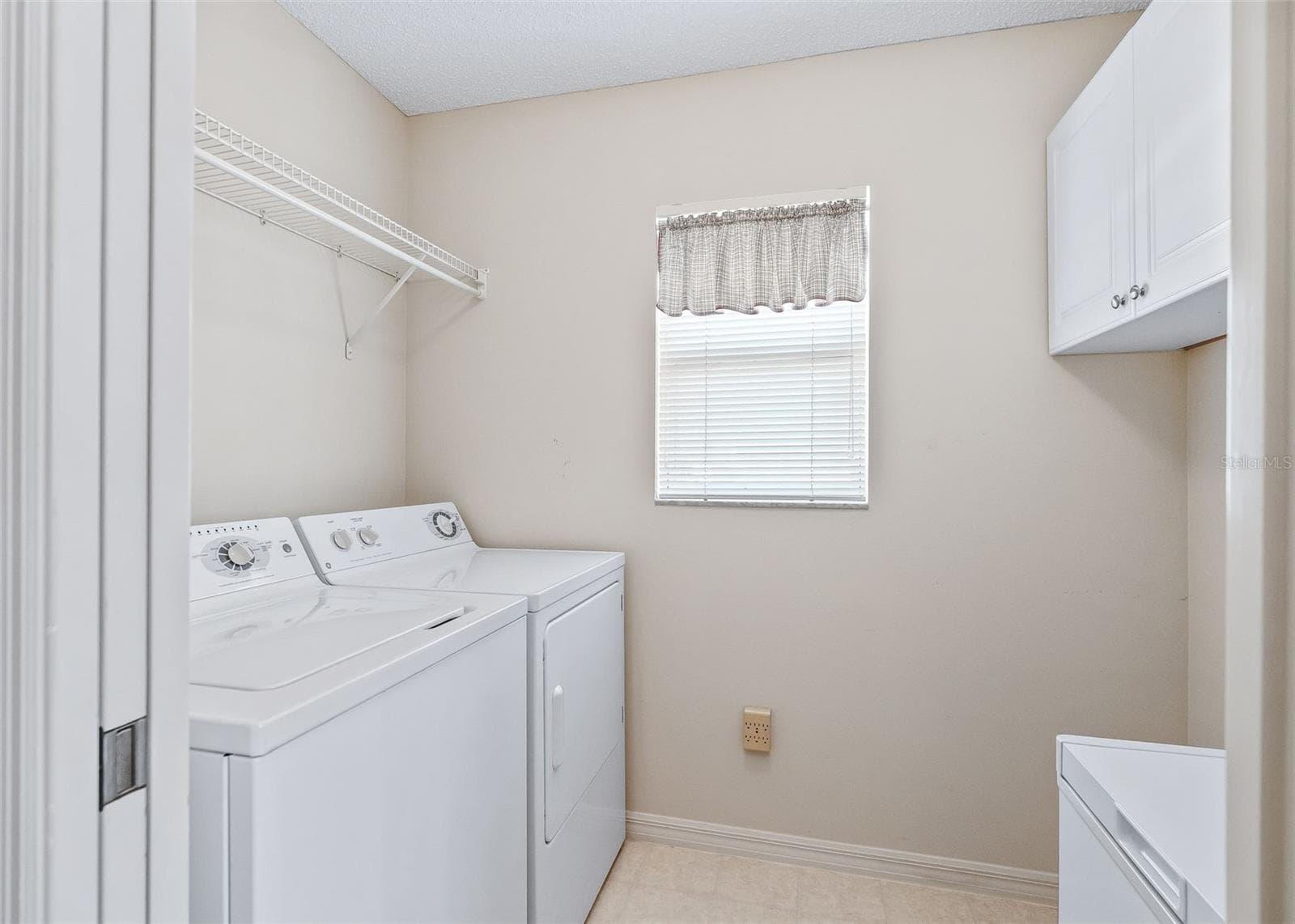 Convenient indoor laundry room featuring a washer and dryer, along with a deep freezer for additional storage. A practical and functional space designed to make everyday household tasks easy and efficient. - 17535 SE 84TH FOXGROVE AVE, THE VILLAGES