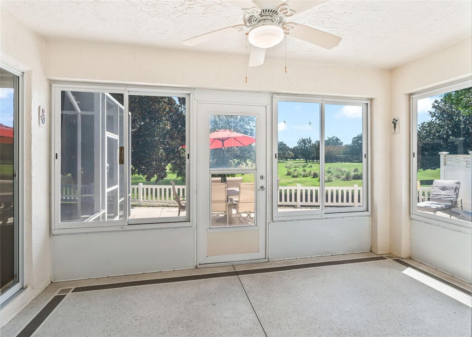 Beautiful enclosed lanai offering a relaxing space to enjoy stunning golf course views. The lanai opens to a lovely private courtyard, creating a peaceful outdoor retreat perfect for morning coffee, entertaining, or simply enjoying the beautiful Florida lifestyle. - 17535 SE 84TH FOXGROVE AVE, THE VILLAGES