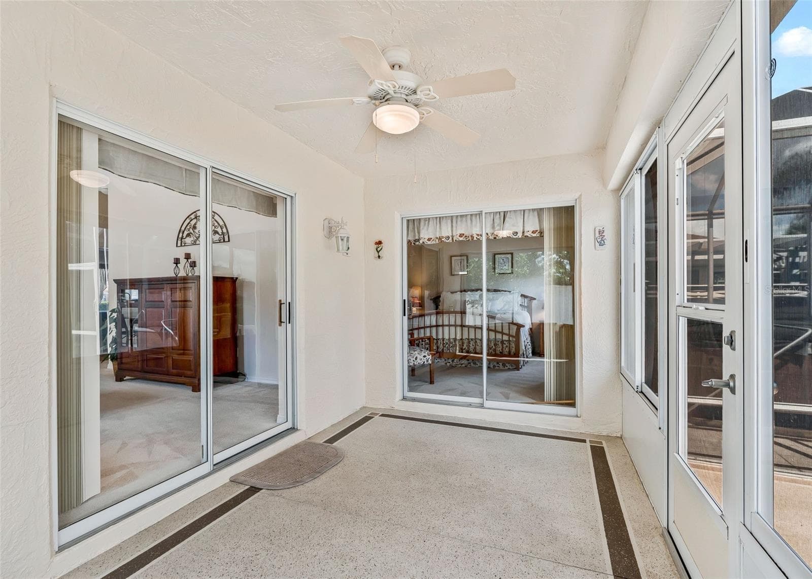 Beautiful enclosed lanai featuring sliding door access to the primary bedroom and a seamless connection to the living room. The lanai opens to a gorgeous private courtyard, creating a peaceful and inviting indoor-outdoor living space perfect for relaxing or entertaining. - 17535 SE 84TH FOXGROVE AVE, THE VILLAGES