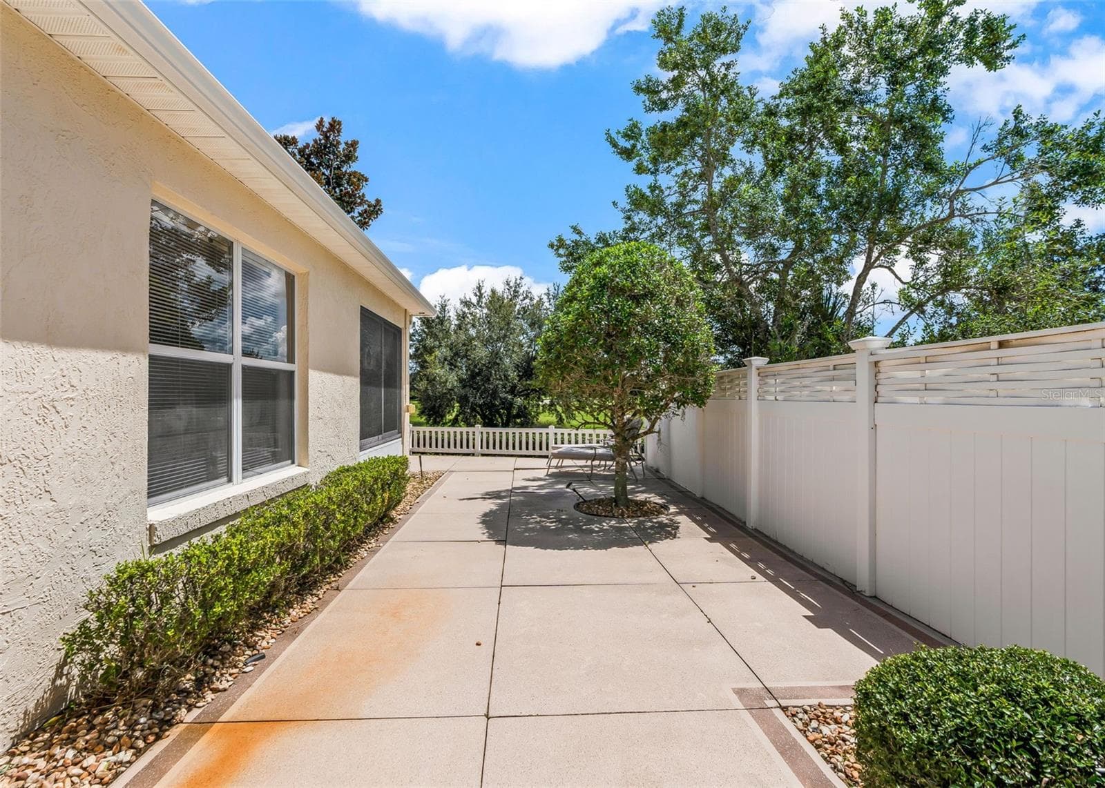 Private courtyard featuring a privacy fence and beautiful mature landscaping, creating a peaceful and secluded outdoor retreat. - 17535 SE 84TH FOXGROVE AVE, THE VILLAGES
