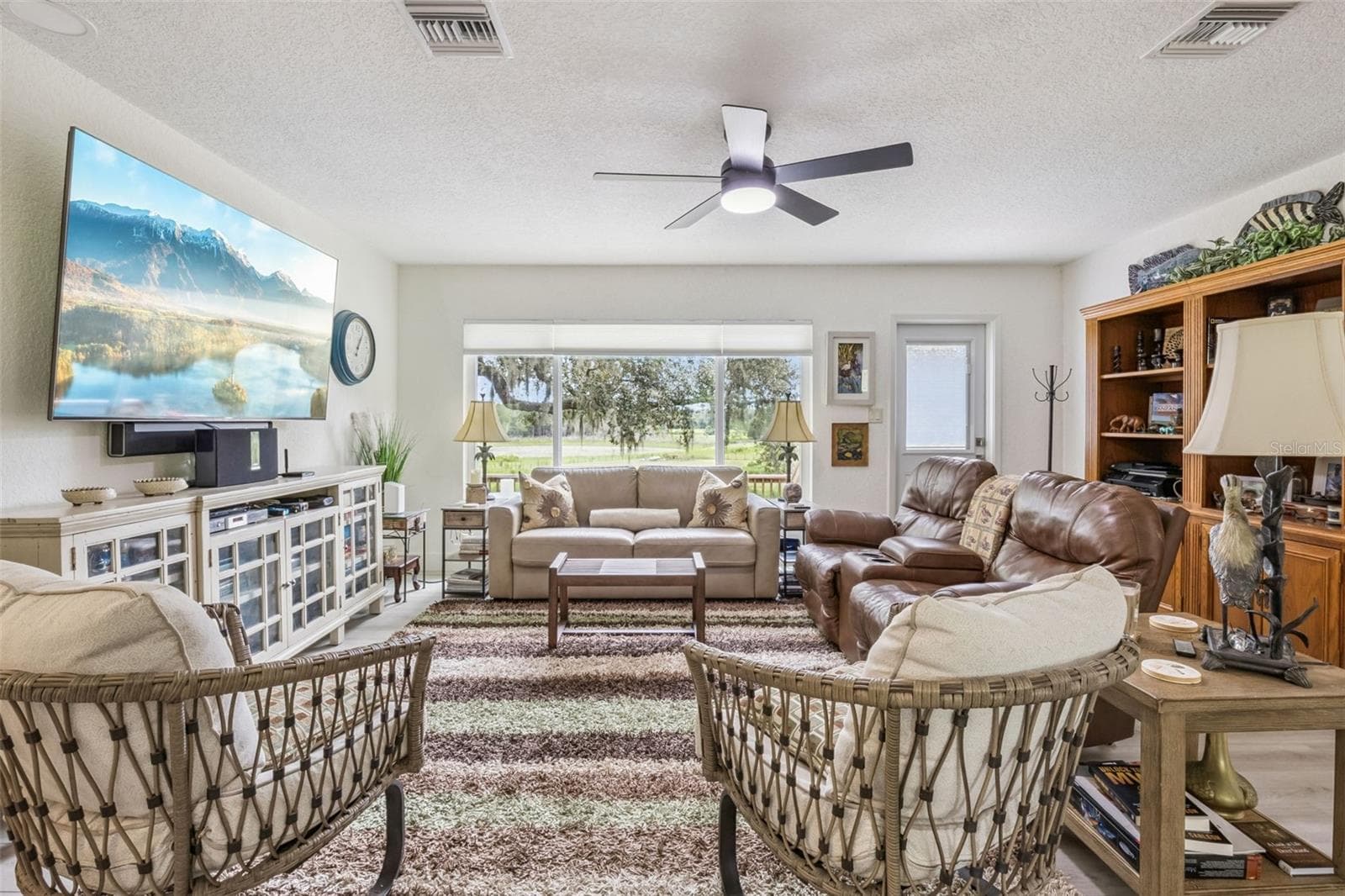 Spacious living room with expansive picture windows framing breathtaking views of rolling green pastures and mature oaks. - 1476 SPRING LAKE RD, FRUITLAND PARK