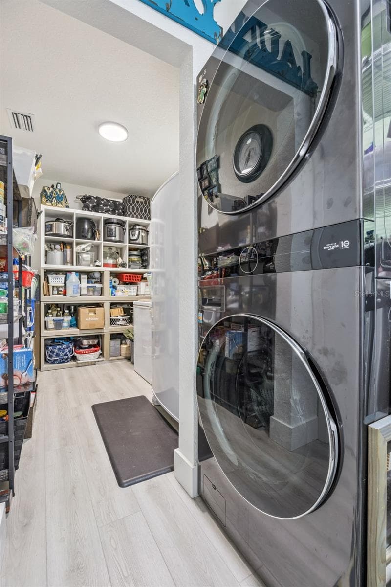 Convenient laundry area with a modern stacked LG washer and dryer, plus a generous walk-in pantry with smart storage solutions. - 1476 SPRING LAKE RD, FRUITLAND PARK