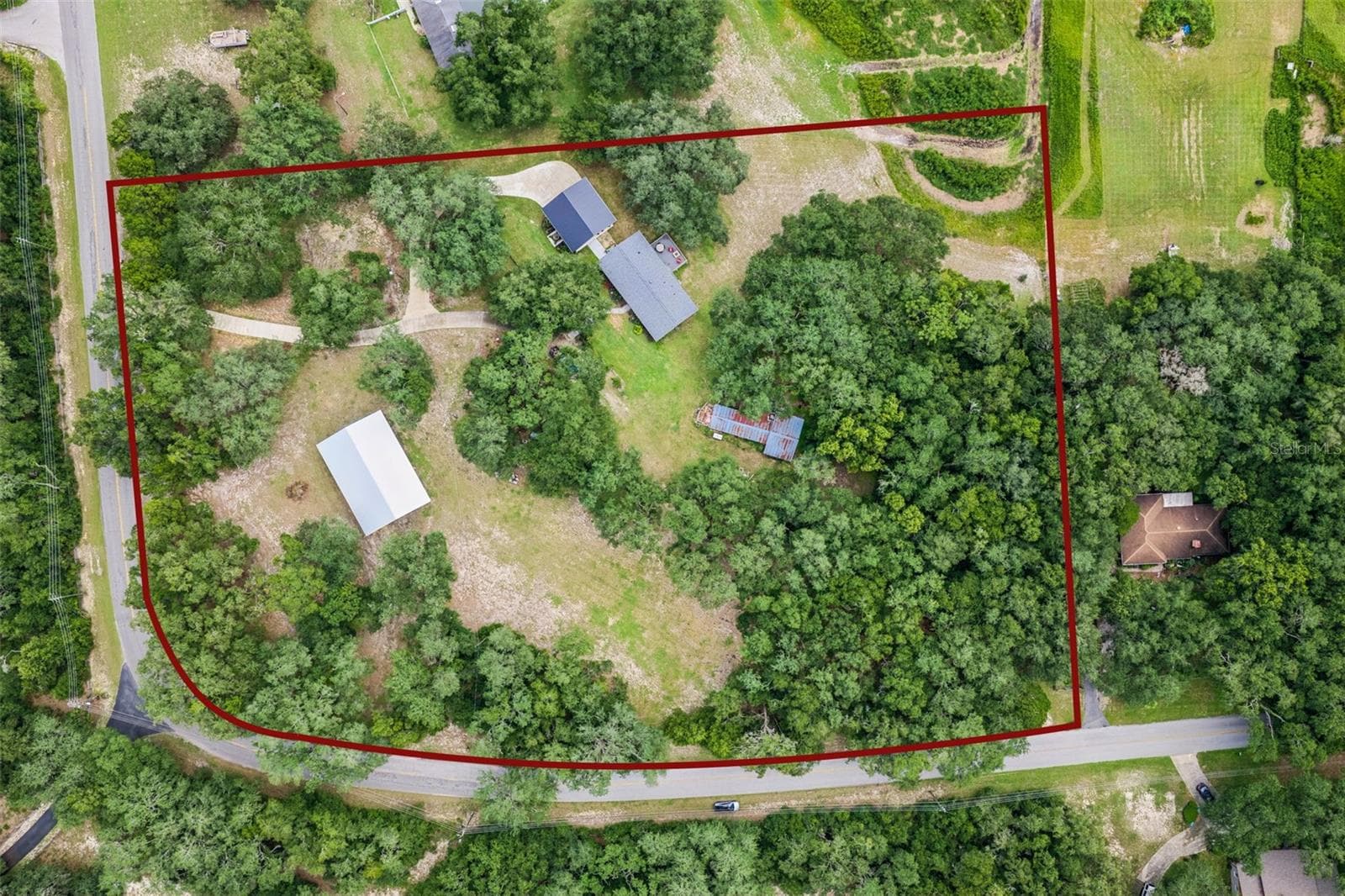 Bird's-eye view showcasing the home's prime position surrounded by mature oaks and open green space. - 1476 SPRING LAKE RD, FRUITLAND PARK