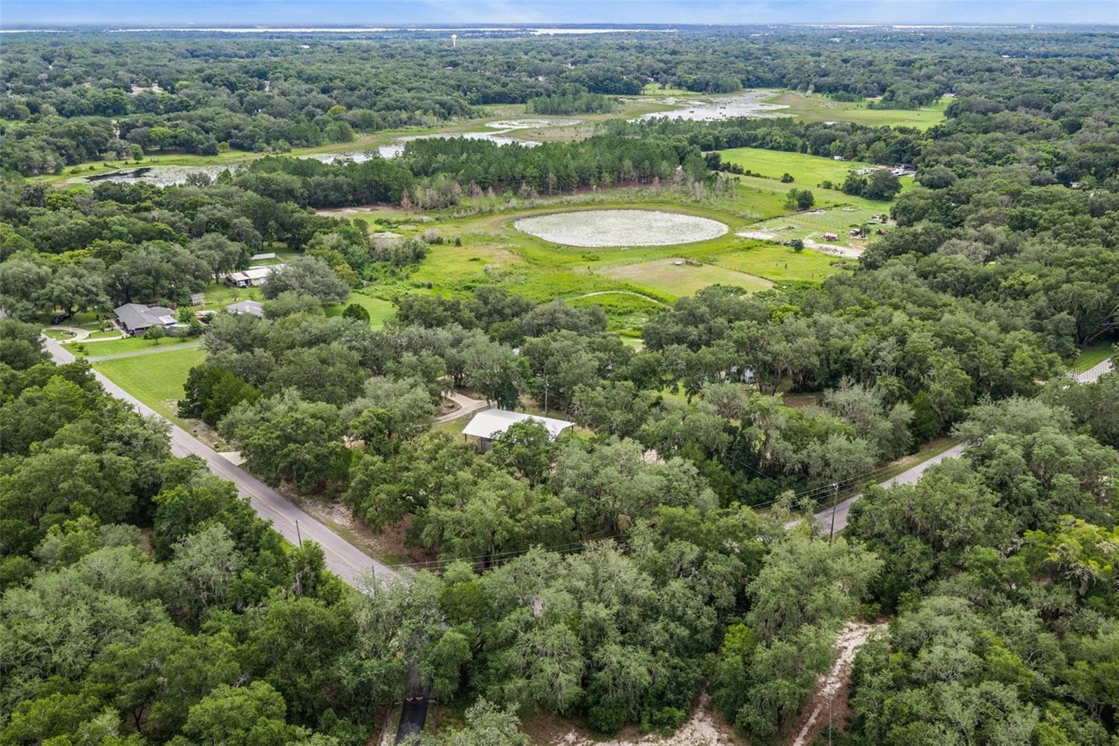 Drone view capturing the home's ideal positioning among towering oaks with expansive views of surrounding farmland. - 1476 SPRING LAKE RD, FRUITLAND PARK