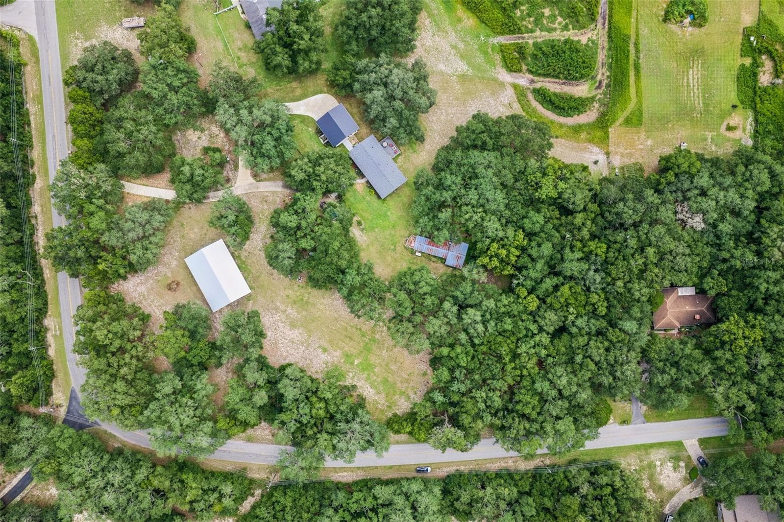 Aerial view of the property showcasing the surrounding landscape and natural canopy. - 1476 SPRING LAKE RD, FRUITLAND PARK