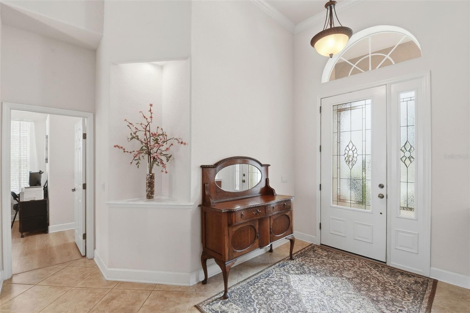 Foyer – Welcoming entry with a decorative glass front door, matching sidelight, arched transom window, and high ceilings for a bright, open first impression. - 114 VIOLA DR, AUBURNDALE