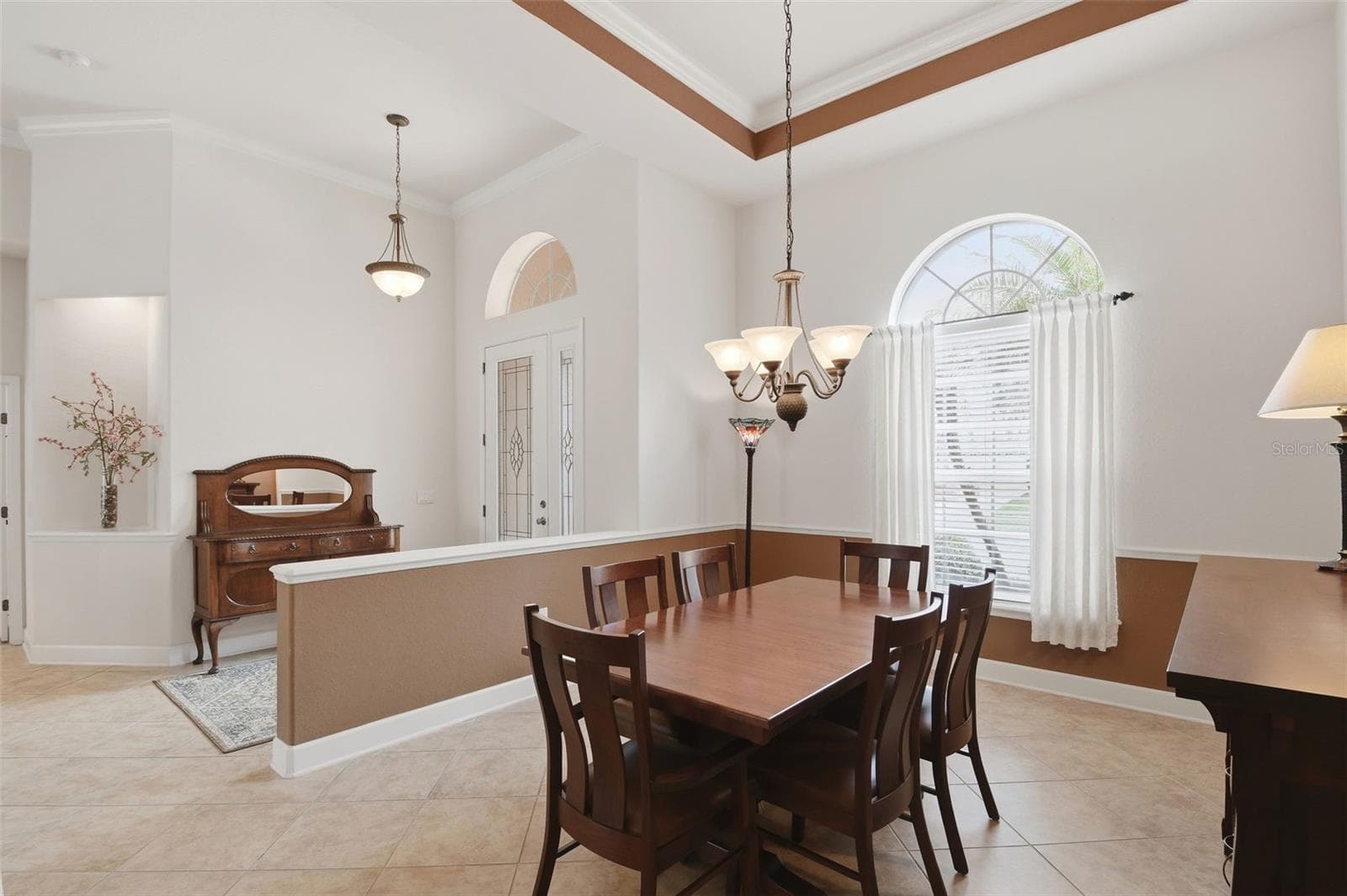 Dining Room – A second dining room view showcases the tray ceiling, chandelier, arched window, and open connection to the foyer for an airy, well-defined entertaining space. - 114 VIOLA DR, AUBURNDALE