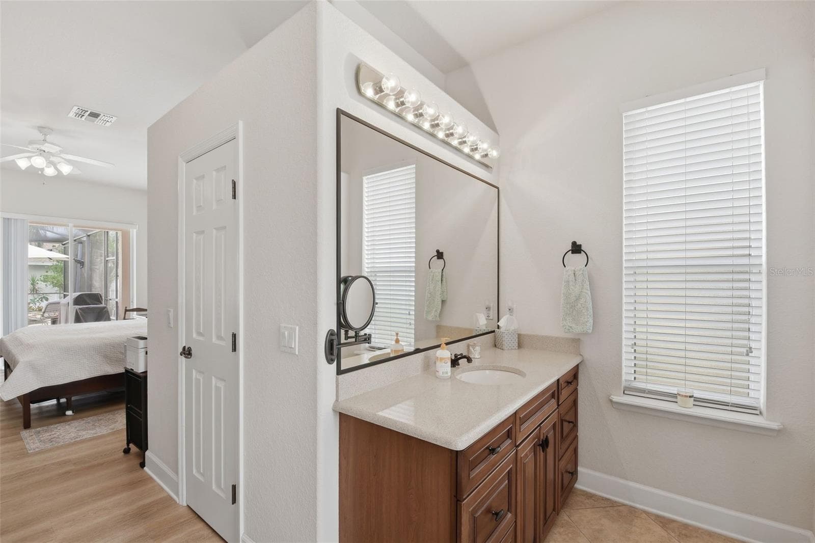 Primary Bathroom – A second bath view highlights an additional vanity area with ample cabinetry, a large mirror, and natural light from the window. - 114 VIOLA DR, AUBURNDALE