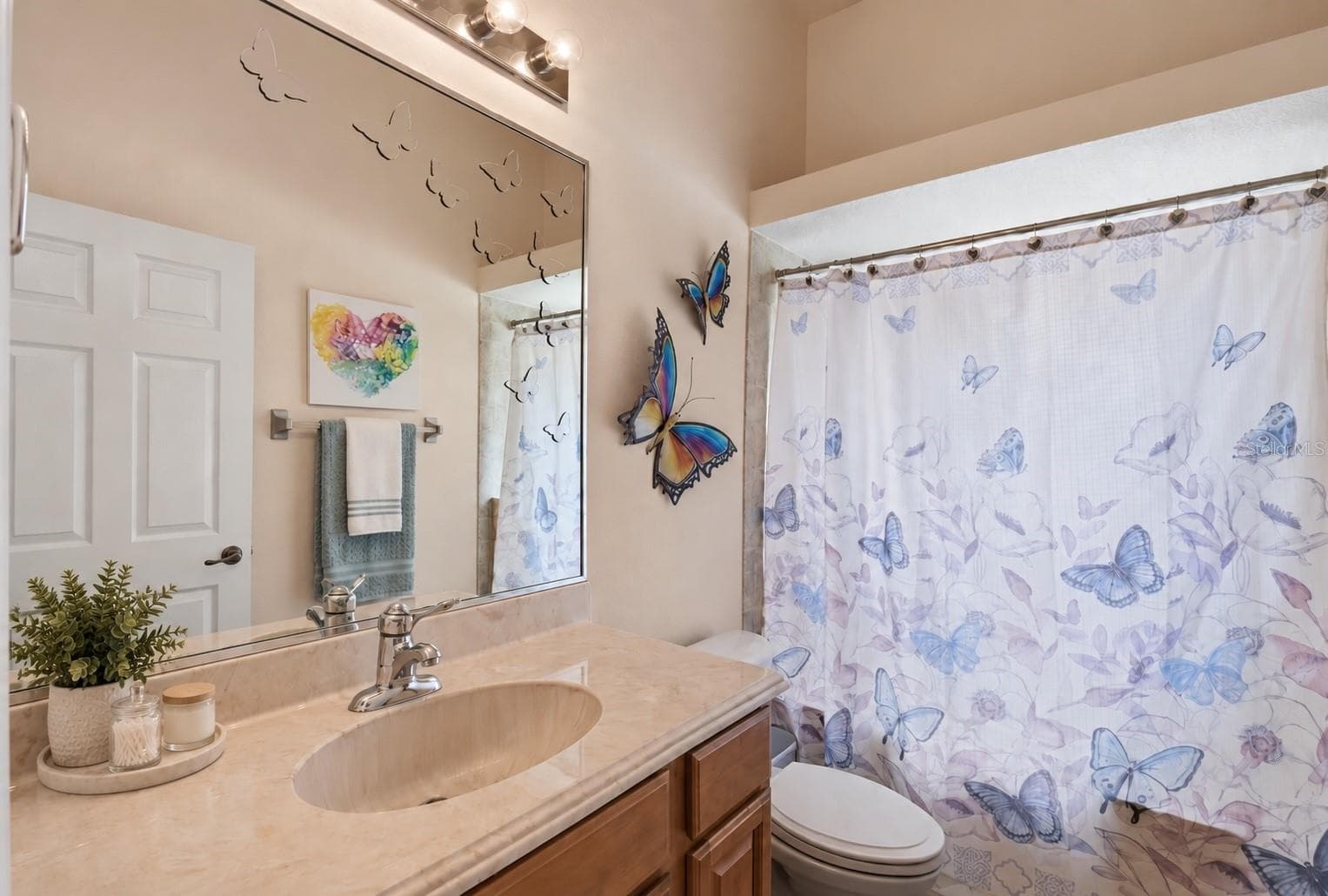 Hall Bathroom – Hall bath with a wood vanity, expansive mirror, and tub/shower combination, finished in neutral tones. - 114 VIOLA DR, AUBURNDALE